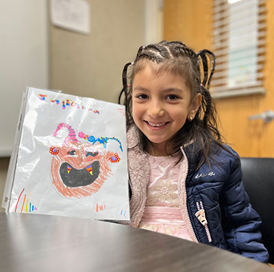 Julianna smiling and holding her artwork with color checking lines at the bottom