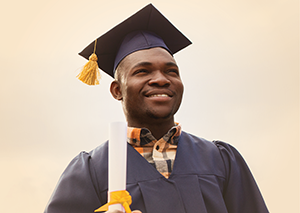 Young African American man in cap and gown smiling confidently holding diploma