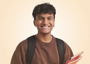 Young man wearing backpack, holding notebooks smiling confidently