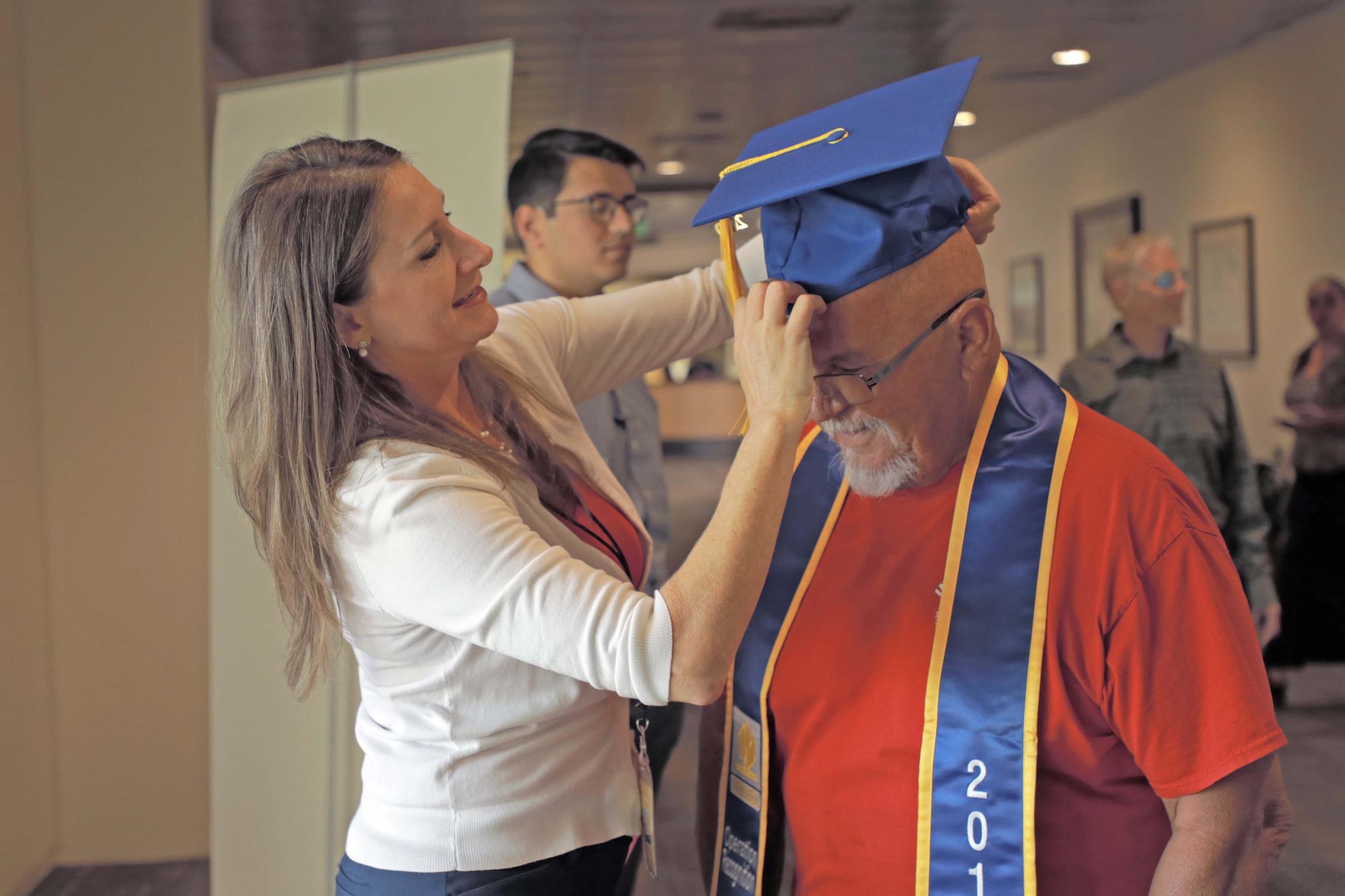 Veteran Richard Granados gets help with graduation cap