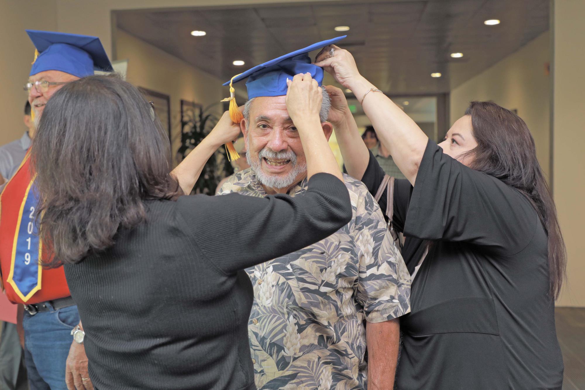 Veteran Raul Garcia gets assistance with graduation cap
