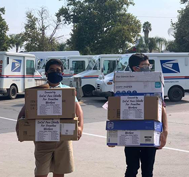 Zubin and Tenzing Carvalho carrying boxes of face shields