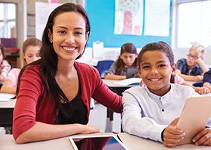 Teacher smiling confidently with elementary student in classroom