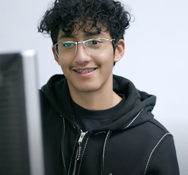 Student smiling confidently while looking at computer screen