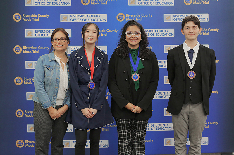 Four student honorees pose in front of Riverside County Mock Trial backdrop